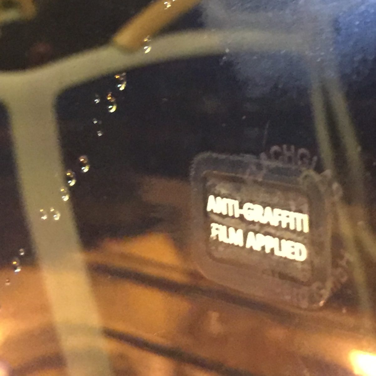 A window with the sticker "anti graffiti film applied"