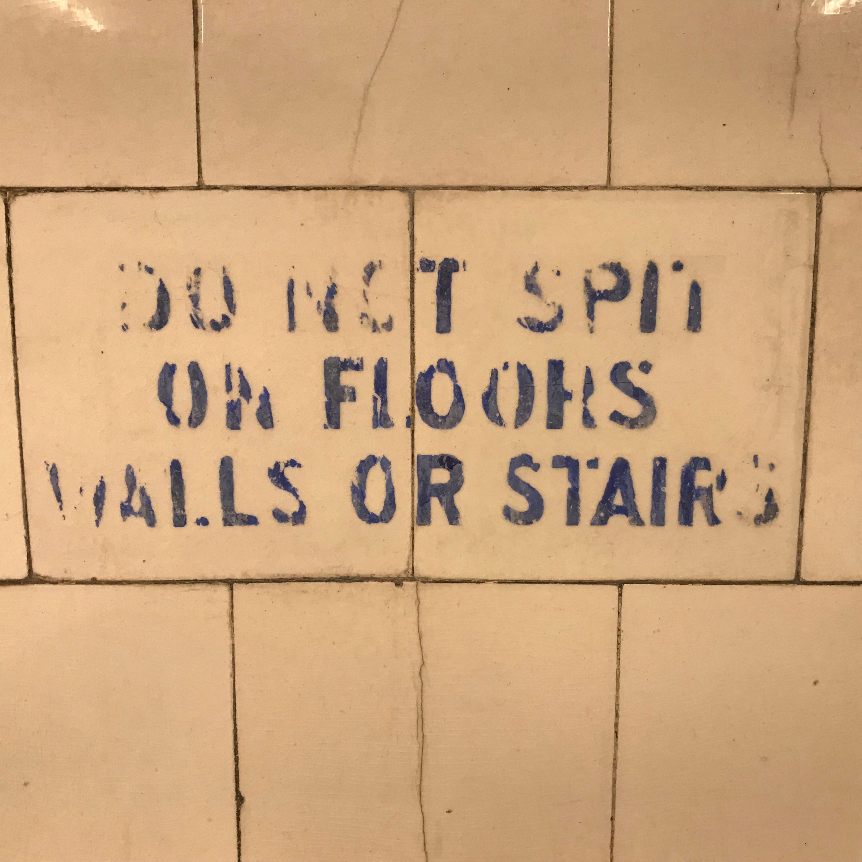 Older style sign instructing people not to spit on walls or floor.