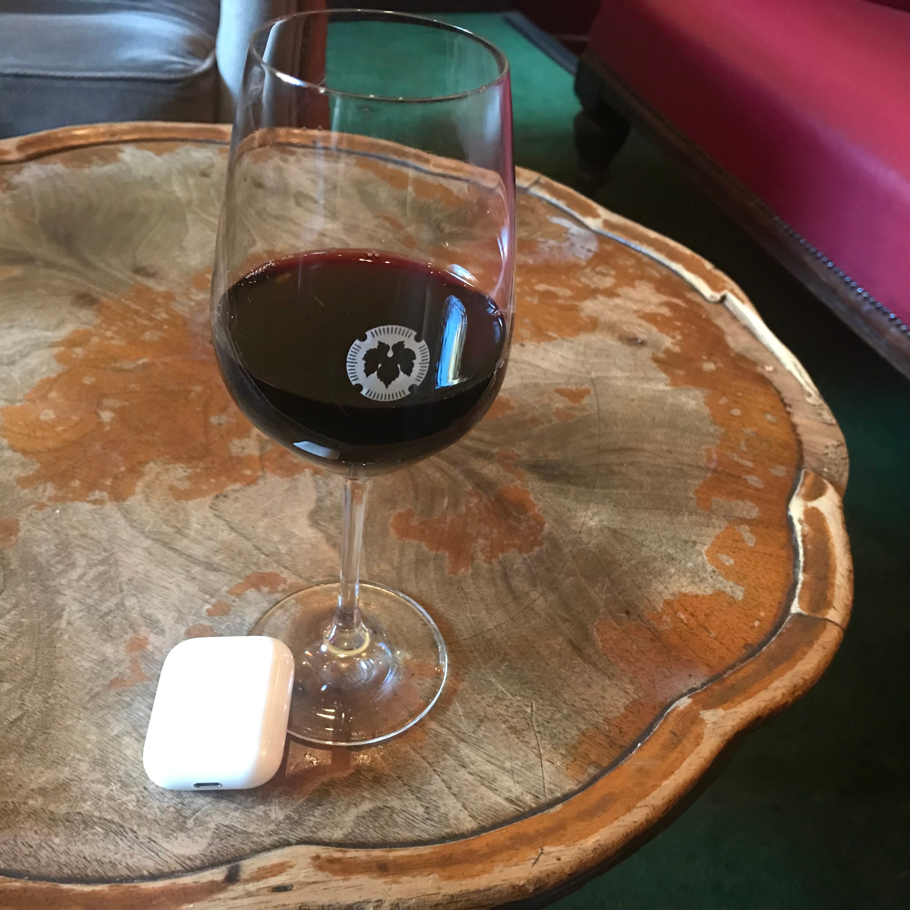 A glass of wine sitting next to an Air pod box