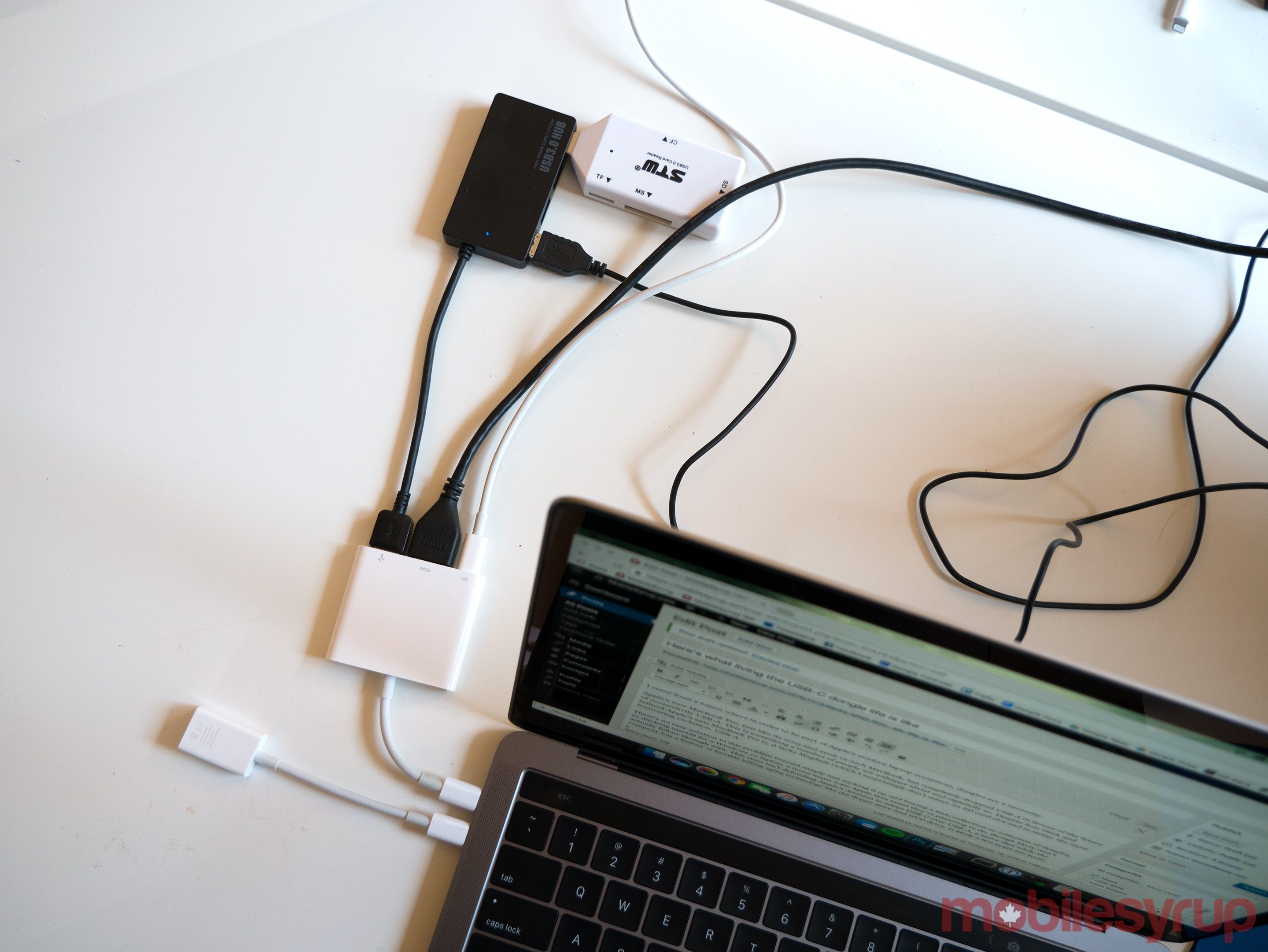 A recent Apple laptop with multiple dongles, some of which are chained.