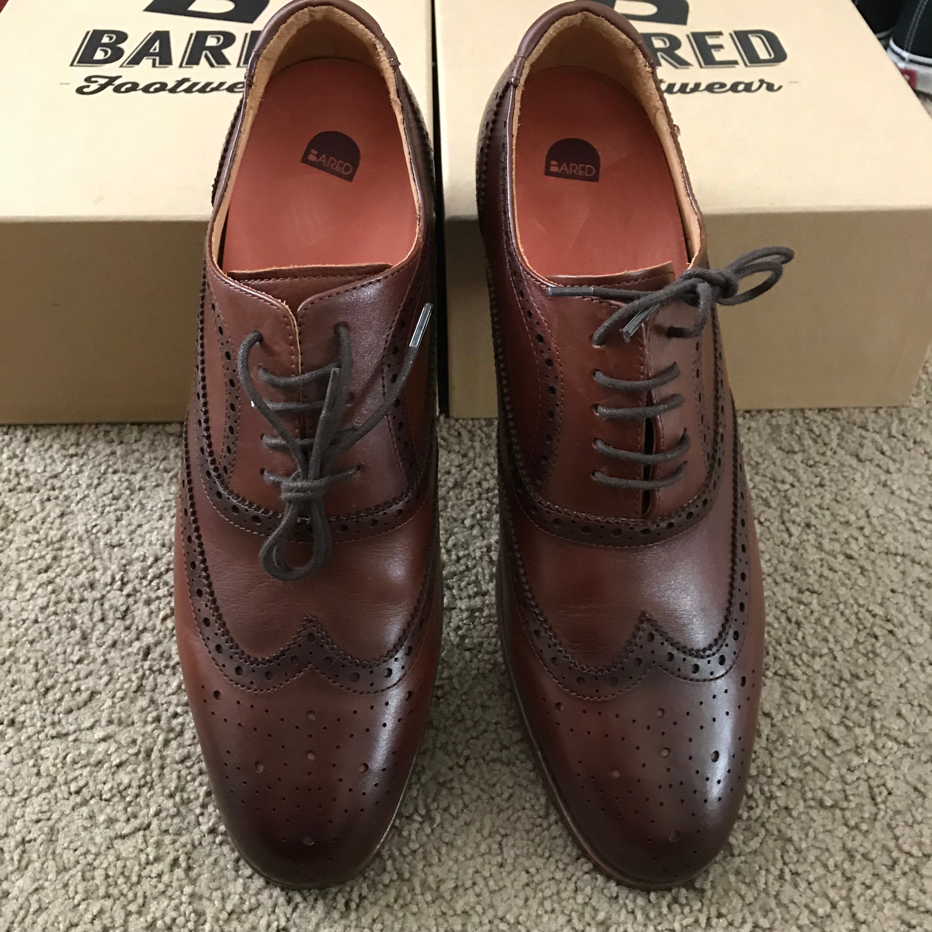 A pair of brown leather brogues leaning against a shoe box