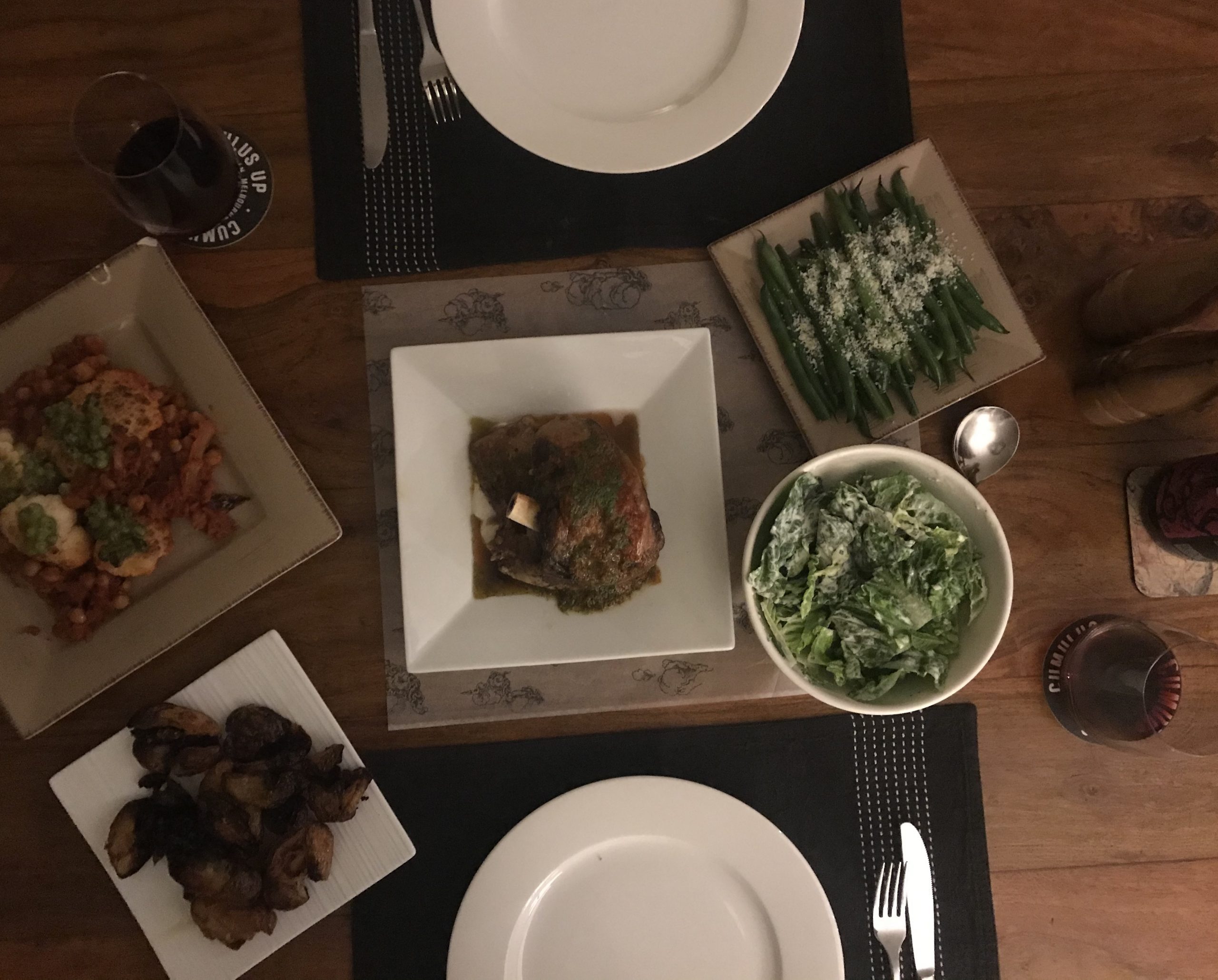 A table laid with a large meal of lamb, potatoes, asparagus, a green salad and wine.