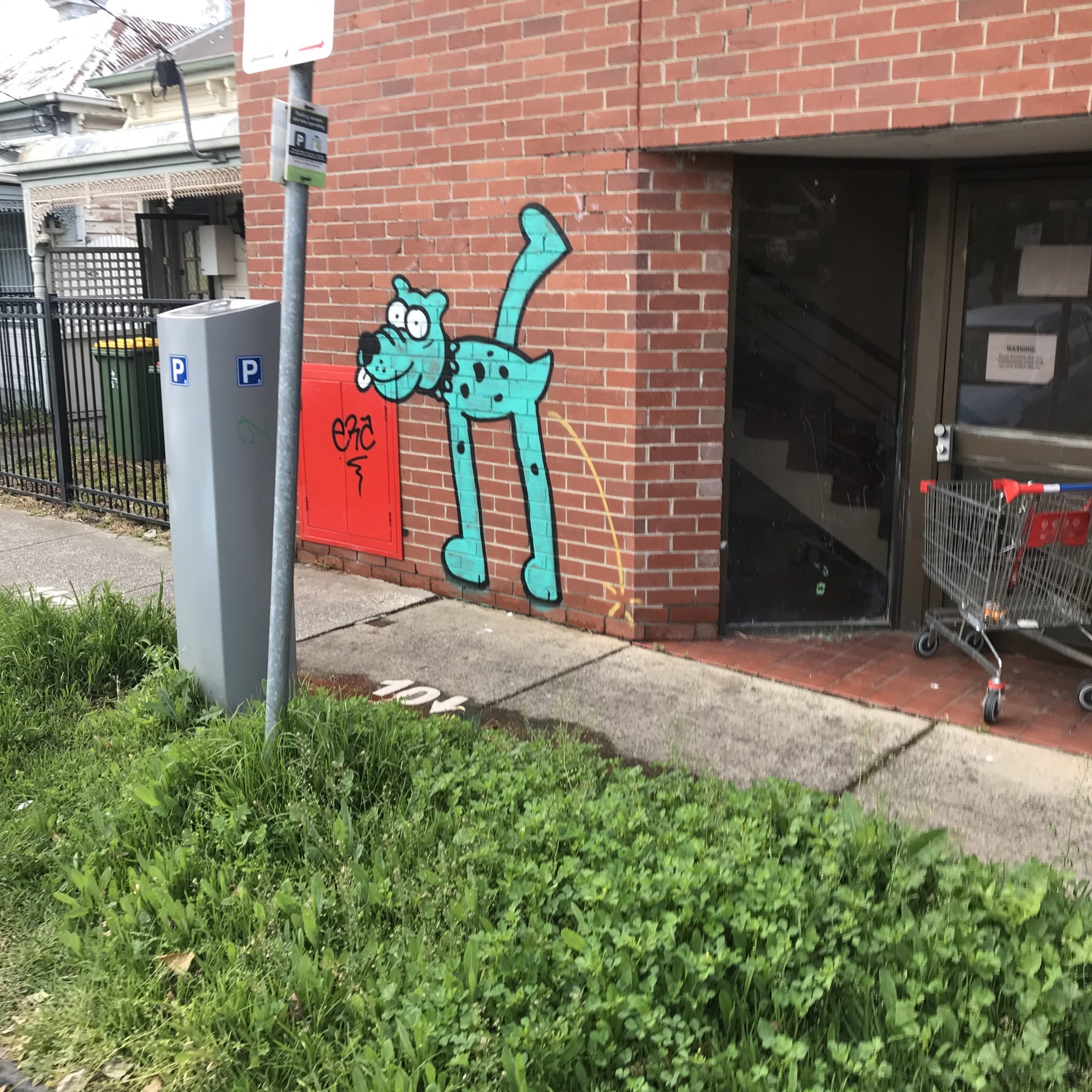 Urinating dog graffitied on a red brick wall and fire hydrant