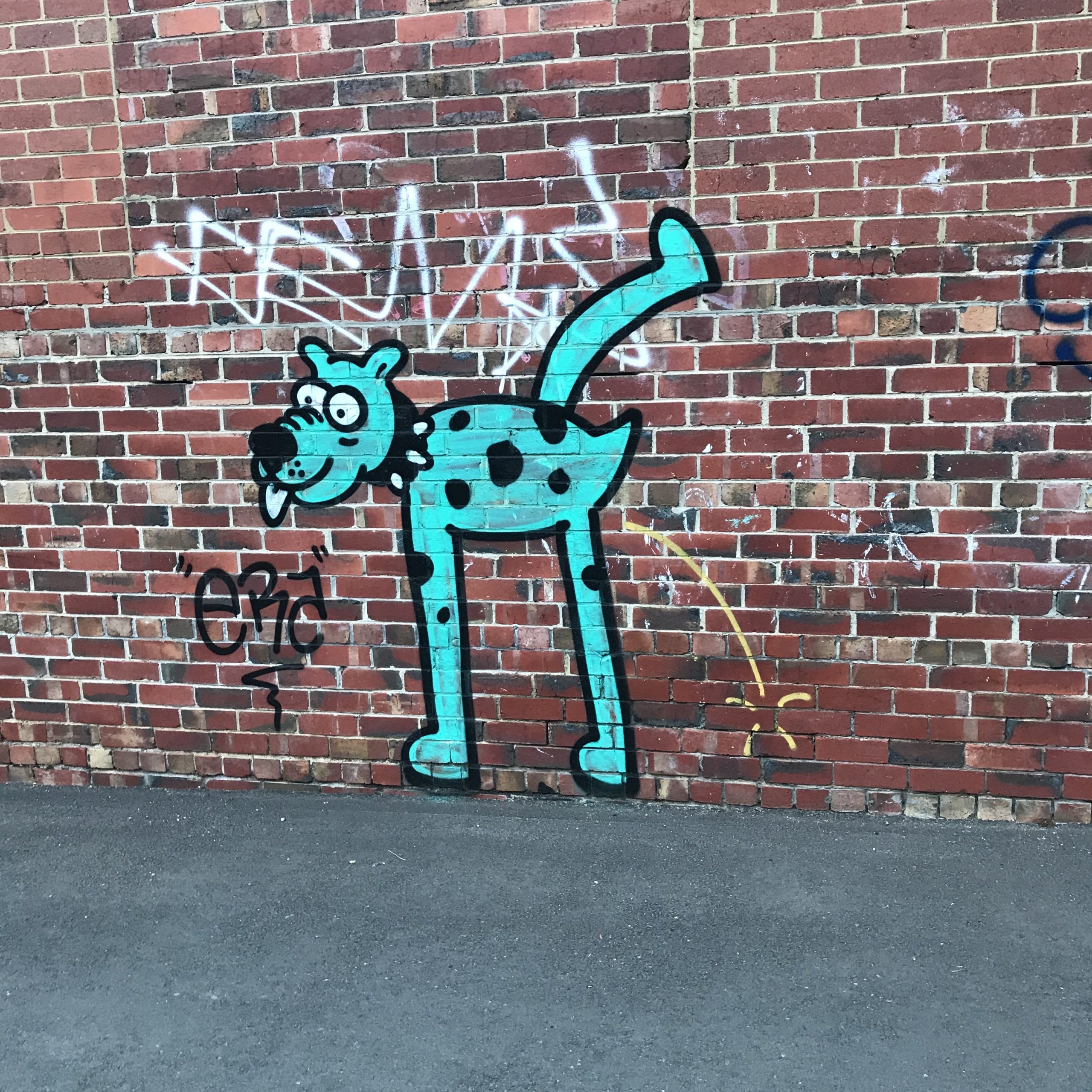 Urinating dog graffitied on an old brick wall