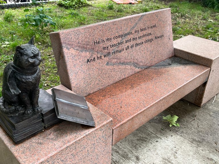 A marble seat with a bronze statue of a cat.