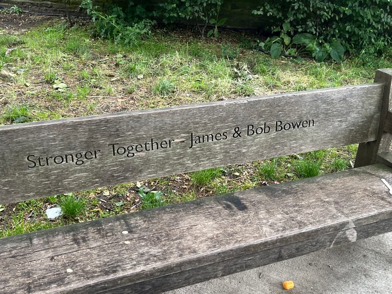 A wooden seat with the engraved text “Stronger together-James and Bob Bowen