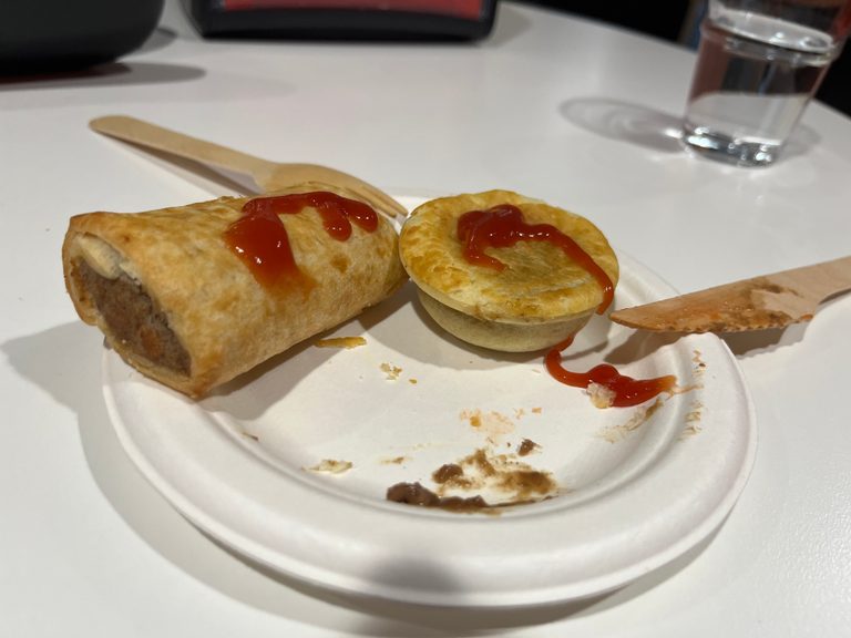 A party pie and sausage roll on a paper plate 
