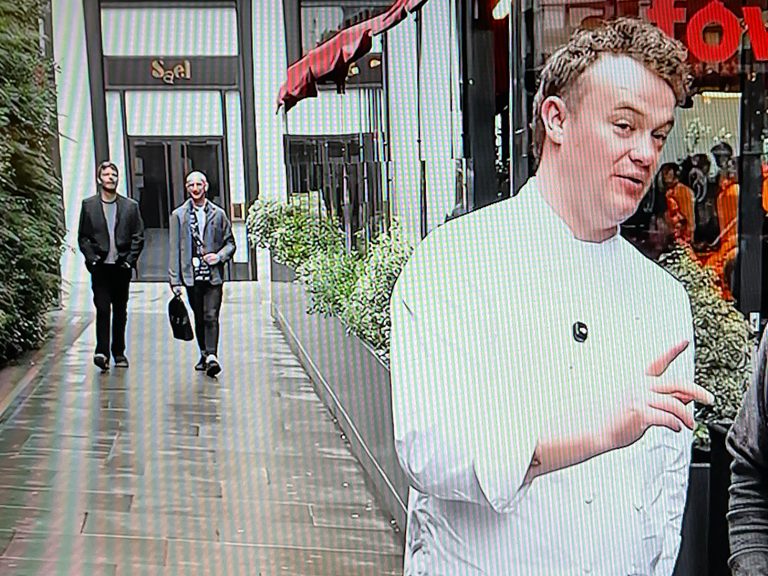 Photo of a video. In the foreground is Will from the Fellow YouTube channel. In the background is my partner and me. 